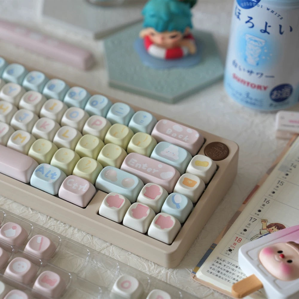 Pastel keycap set in a tray, featuring heart and paw icon keys