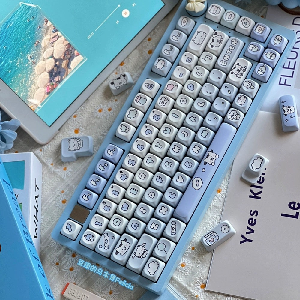 Blue keyboard keycap set with white cat and cloud icons, with several loose keys shown