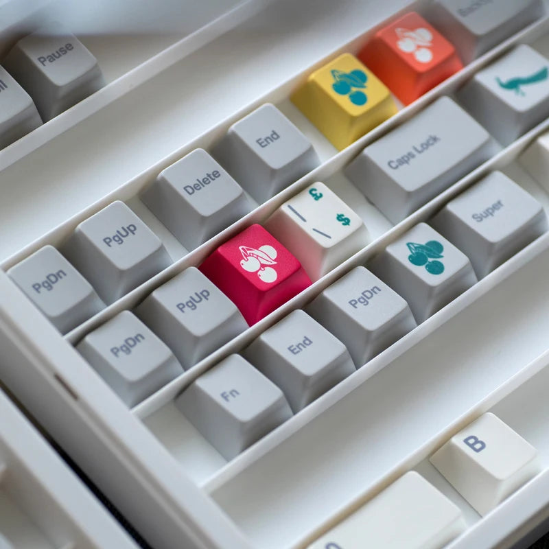 Keycap set close-up with white keys and colorful accent keys, including a pink paw icon.