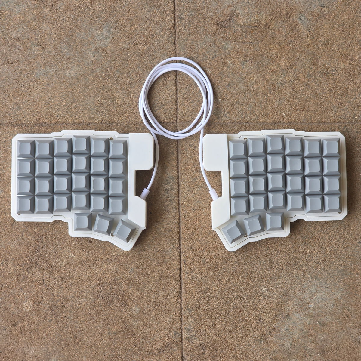 Split wired keyboard with light gray keycaps and white cable, two-piece layout