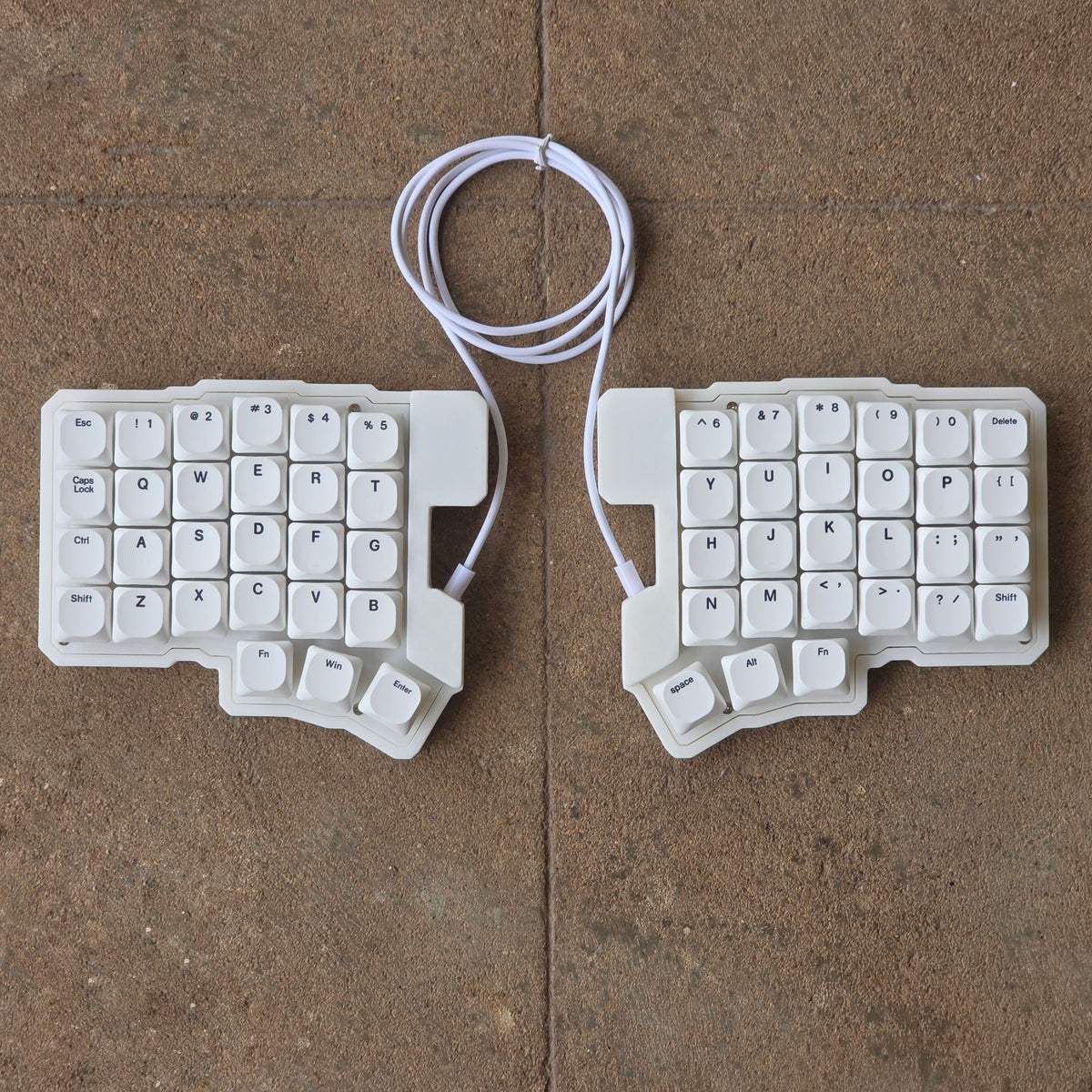 Split wired keyboard with white keycaps, light base, white cable, front view pair.