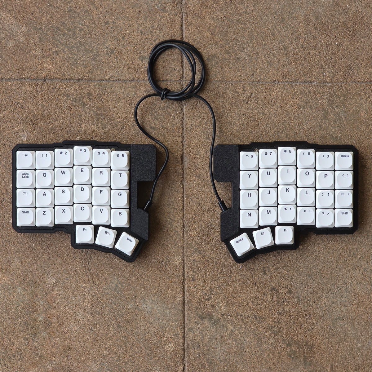 Split wired keyboard with white keycaps and black cable, two-piece layout