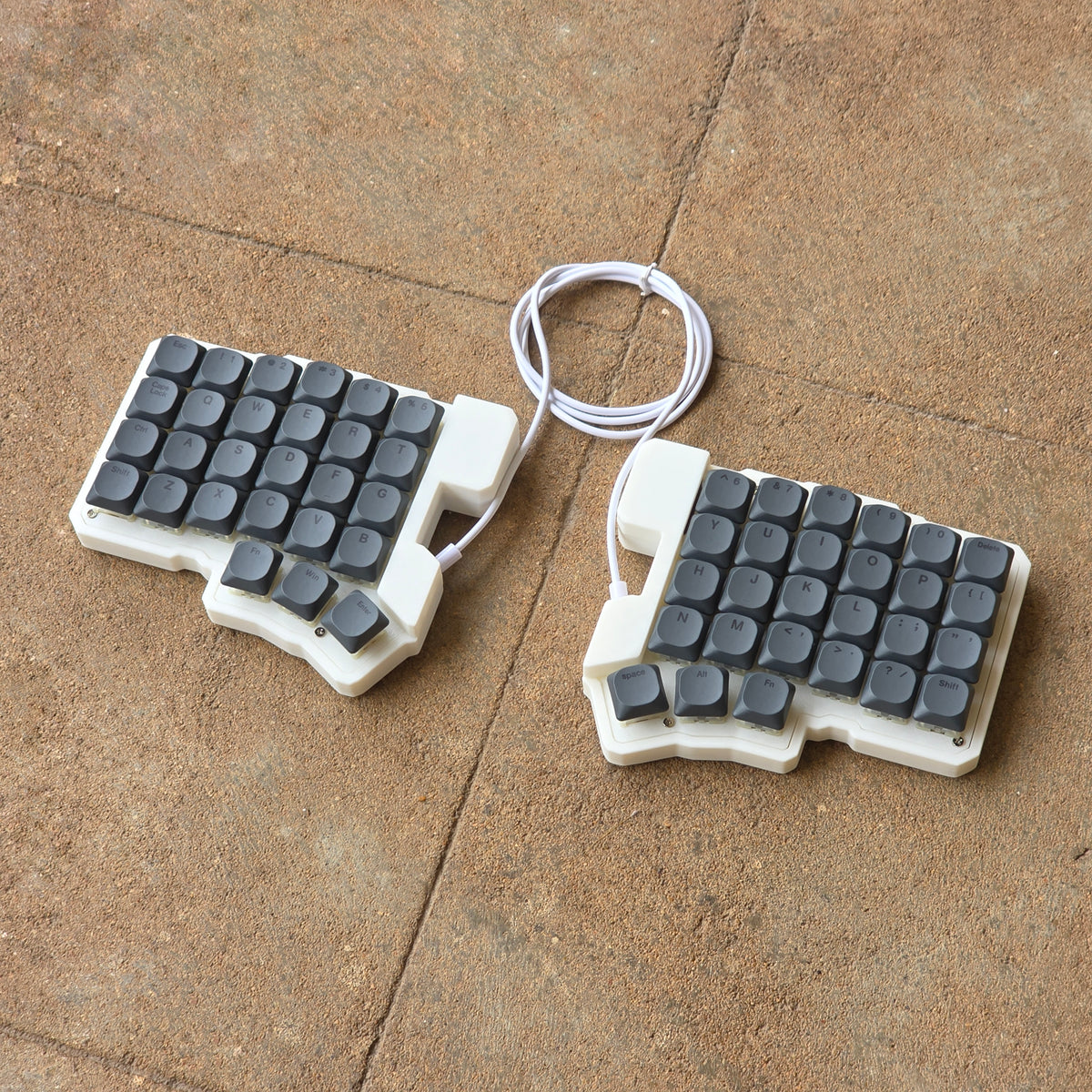 Split wired keyboard with dark gray keycaps and white cable, two-piece layout