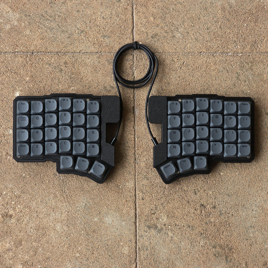 Split wired keyboard with dark gray keycaps and black cable, two-piece layout