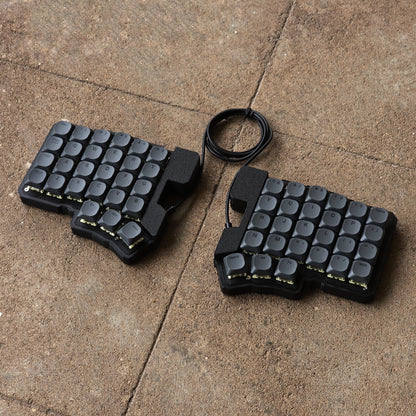 Split wired keyboard with dark gray keycaps and black cable, compact two-piece layout