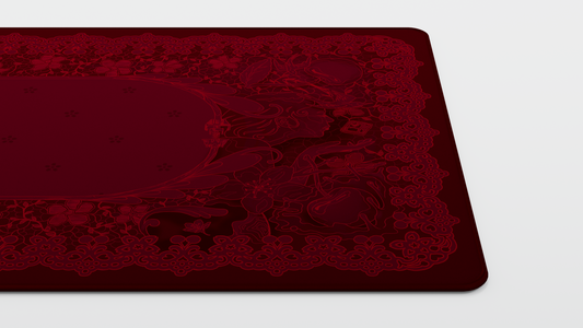 Red deskmat corner with detailed floral pattern and centered oval motif