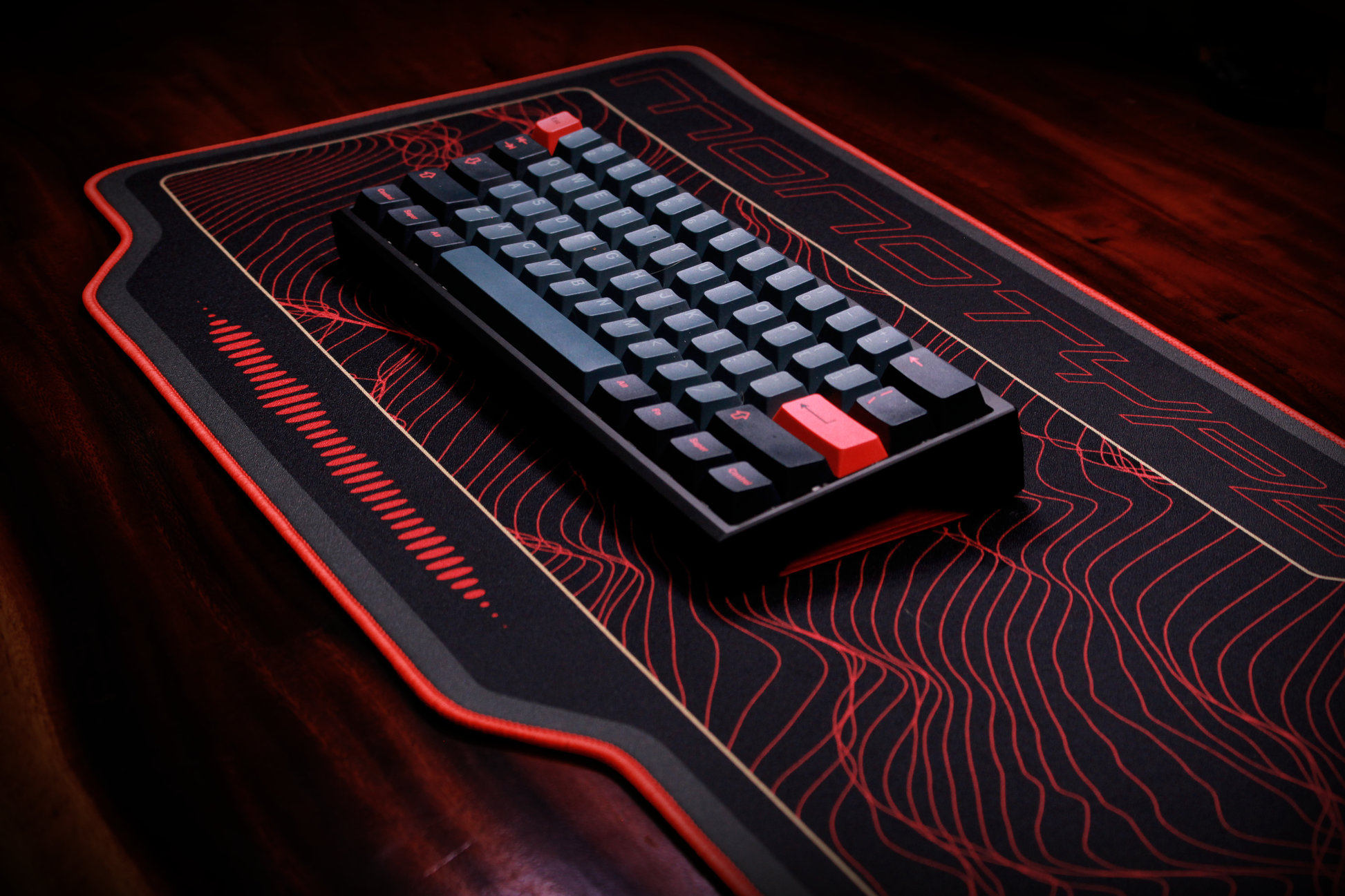 Crimson desk mat with red topographic lines, dark center panel, and red edge trim