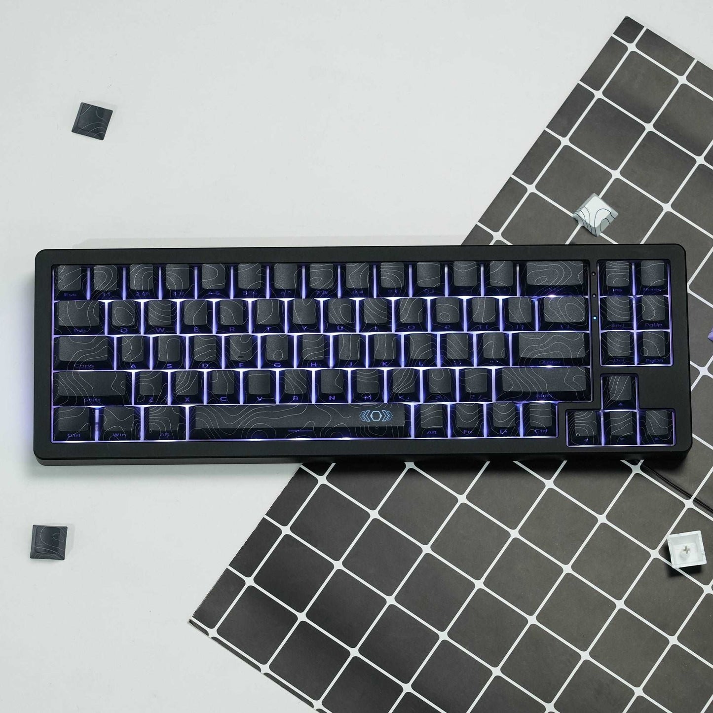 Black topographic keycap set with blue backlit outlines and stepped legends