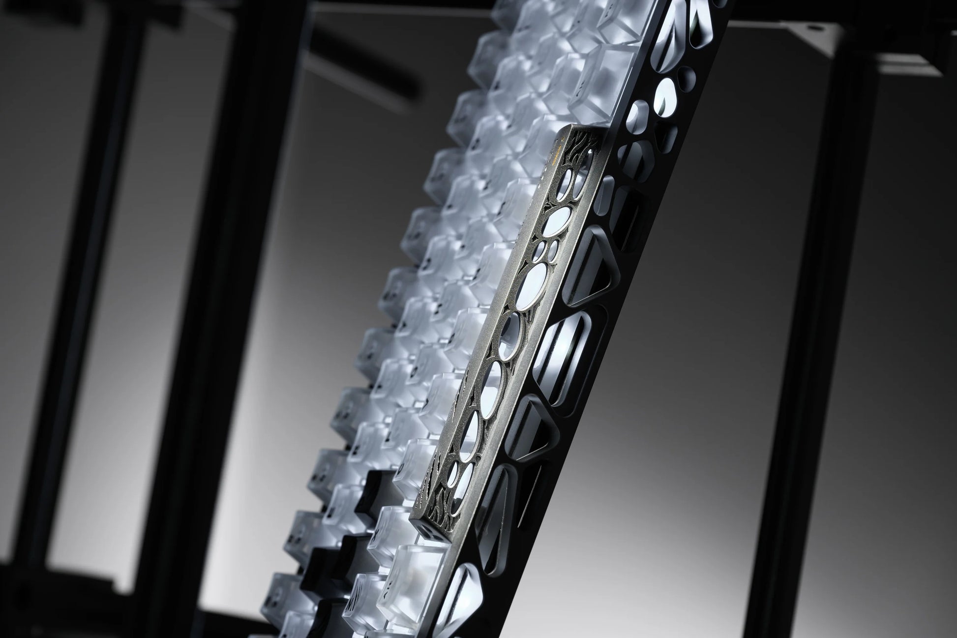 Side view of keycap tray showing stacked dark keycaps and metal frame