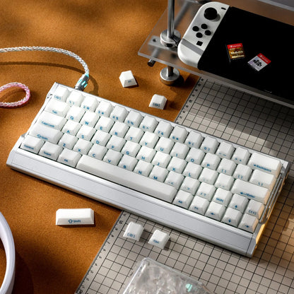 Mechanical keyboard with white keycaps and side engraving; keyboard on a work surface