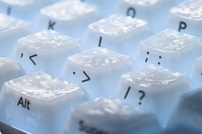 Set of white keycaps with symbols and letters on a light tray